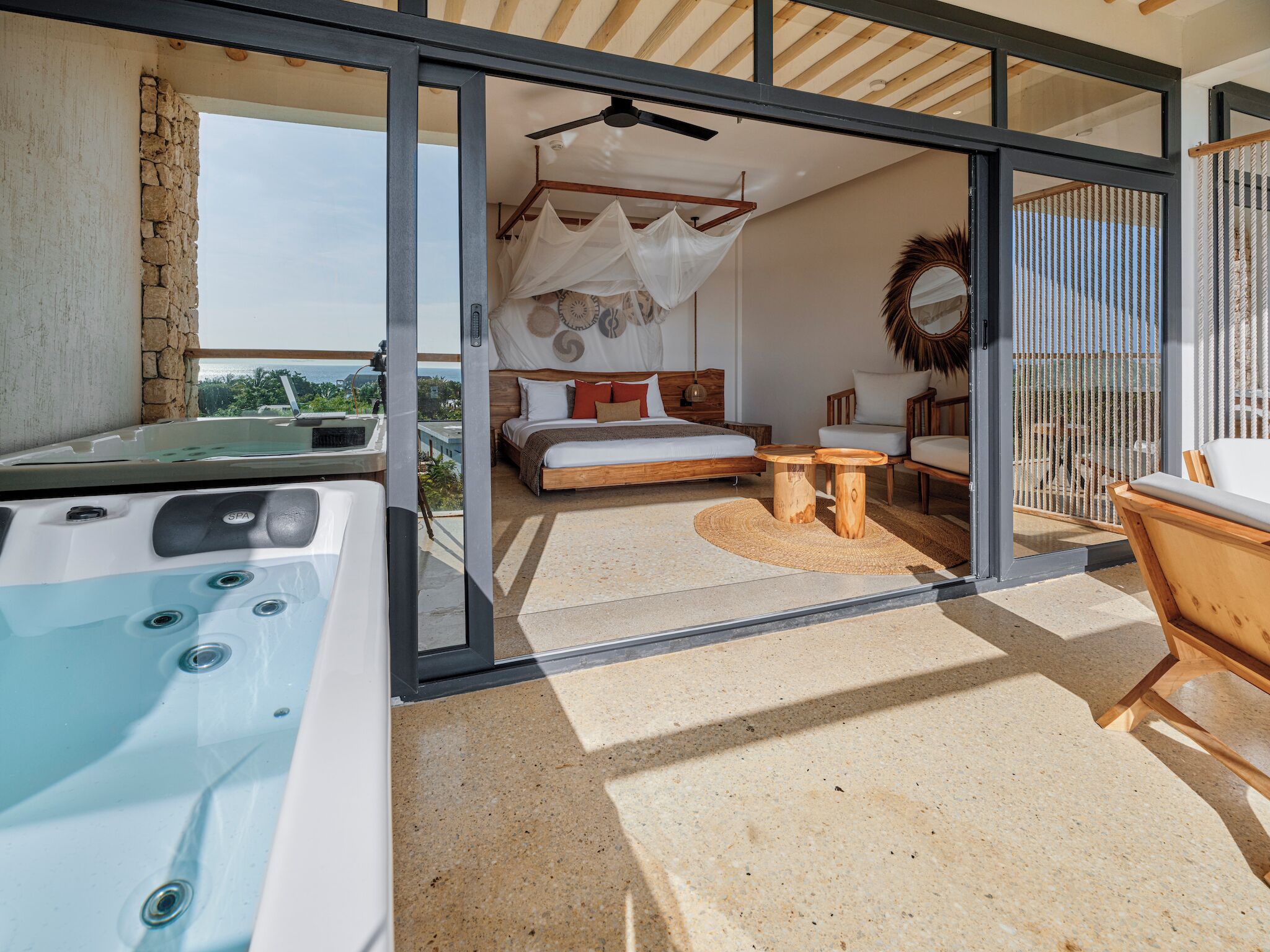 Quarto moderno com cama, mesa de cabeceira e vista para o exterior.