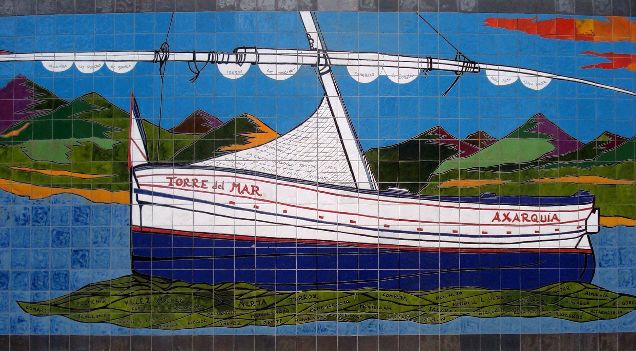 A mosaic of a boat named 'TORRE del MAR' with 'AXARQUIA' written on it, set against a backdrop of mountains and a blue sky.