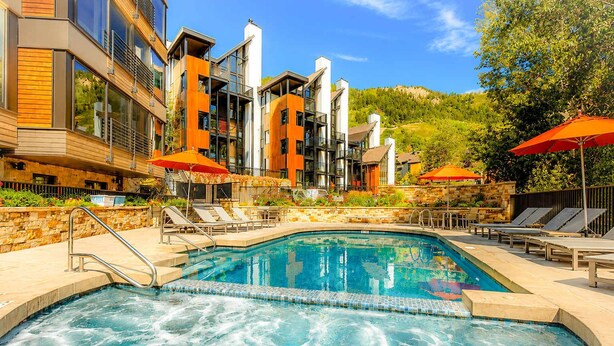 A modern hotel with a swimming pool, lounge chairs, and outdoor umbrellas. - Updated Core 3 BR, 3 BA with AC, Pool & Hot-tub! (Aspen)