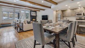 A modern living room with a fireplace, dining area, and kitchen. - Updated Core 3 BR, 3 BA with AC, Pool & Hot-tub! (Aspen)