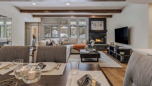 A modern living room with a fireplace, a television, and a dining area set for a meal. - Updated Core 3 BR, 3 BA with AC, Pool & Hot-tub! (Aspen)