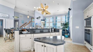 Cocina amplia con una isla central, armarios blancos y un ventanal con vistas.