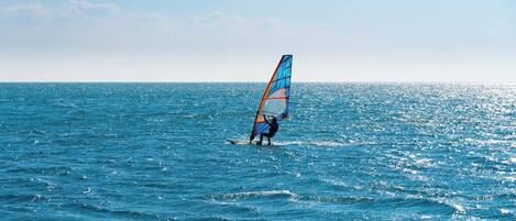 A person windsurfing on a calm sea.