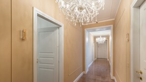 A hallway with beige walls and a polished floor, leading to a door with a white frame. - Casa dei Liuti (Alghero)