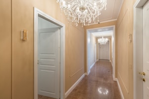 Un pasillo con paredes color crema y piso pulido, que conduce a una puerta con marco blanco.