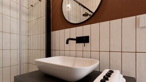 A bathroom with a white vessel sink, a black faucet, and a towel rack with towels. - Casa dei Liuti (Alghero)