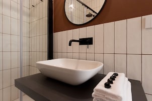 Un bagno con un lavabo a incasso bianco, un rubinetto nero e un porta asciugamani con asciugamani.