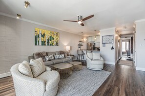 A modern living room with a grey sofa, a patterned armchair, and a round coffee table. A ceiling fan and recessed lighting are visible. - Wild Blue Vue | Stylish 1BR Retreat Steps from the Gondola | Sleeps 4! (Steamboat Springs)