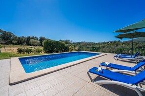 A rectangular swimming pool with blue tiles, surrounded by beige tiles, and blue lounge chairs with white cushions. - Rural finca pool Es Sementaret in Mallorca (Arta)