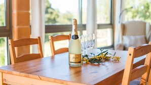Une table en bois avec une bouteille de cava Freixenet, des verres et des fleurs jaunes.