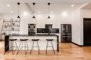 Enjoy cooking in this well-lit kitchen with an oven, refrigerator, and sleek island with bar stools.