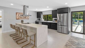 A modern kitchen with a marble island, stainless steel appliances, and a view of the outdoors.