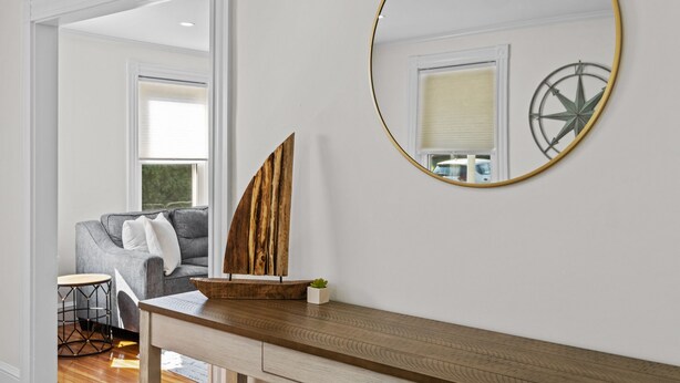 Una sala de estar moderna con una mesa de centro de madera, un sofá gris y un espejo redondo con marco dorado.