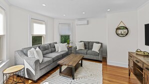 Una sala de estar moderna con un sofá seccional gris, una mesa de centro de madera y una alfombra blanca.