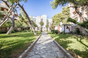 A pathway leading to a building with a stone facade, surrounded by greenery and trees.