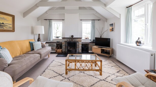 A spacious living room with a high ceiling, a fireplace, a television, and a cozy seating area.