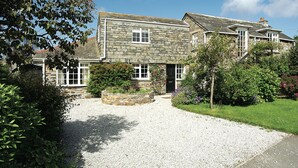A stone house with a gravel driveway and a garden.