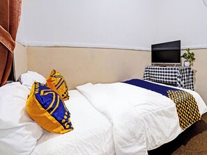 A hotel room with a bed, pillows, a television, and a small table with a plant. - Spot On 91425 Mekargalih Homestay Syariah (Mekargalih)