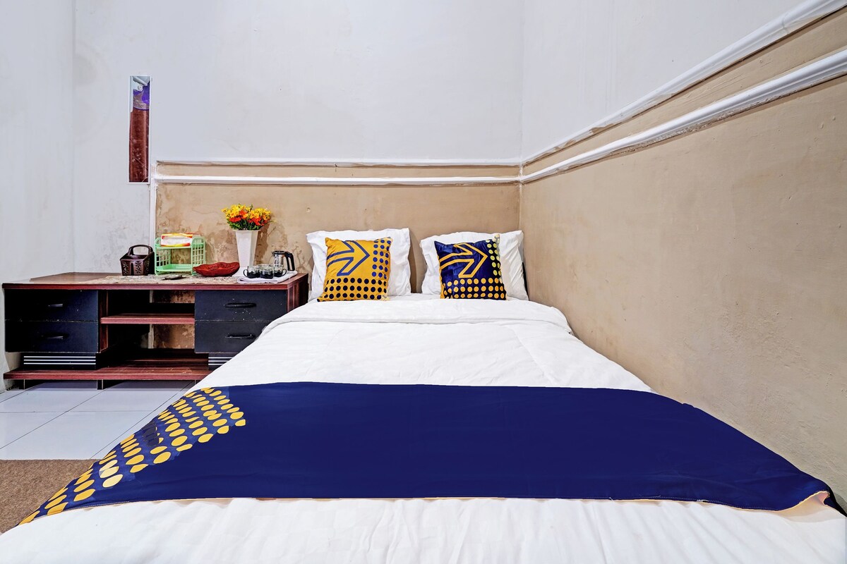 A hotel room with a bed, a desk, and a nightstand.