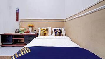 A hotel room with a bed, a desk, and a nightstand.