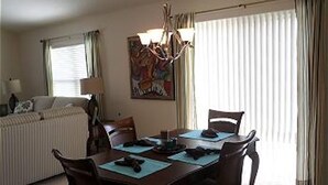 A dining area with a table set for four, a chandelier, and a painting on the wall. - 741 Adrienne Way (Wildwood)