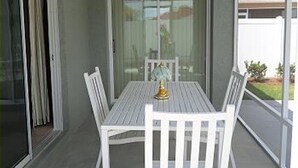 A covered patio with a table and chairs, a glass door, and a view of a house and landscape. - 741 Adrienne Way (Wildwood)