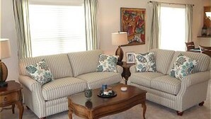 A living room with two striped sofas, a wooden coffee table, and a painting on the wall. - 741 Adrienne Way (Wildwood)