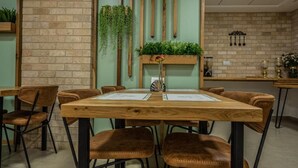 A restaurant with a brick wall, wooden beams, and hanging plants.