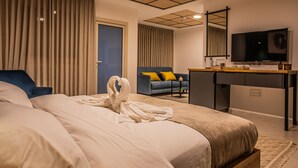 A hotel room with a bed, a desk, a TV, and a sofa.