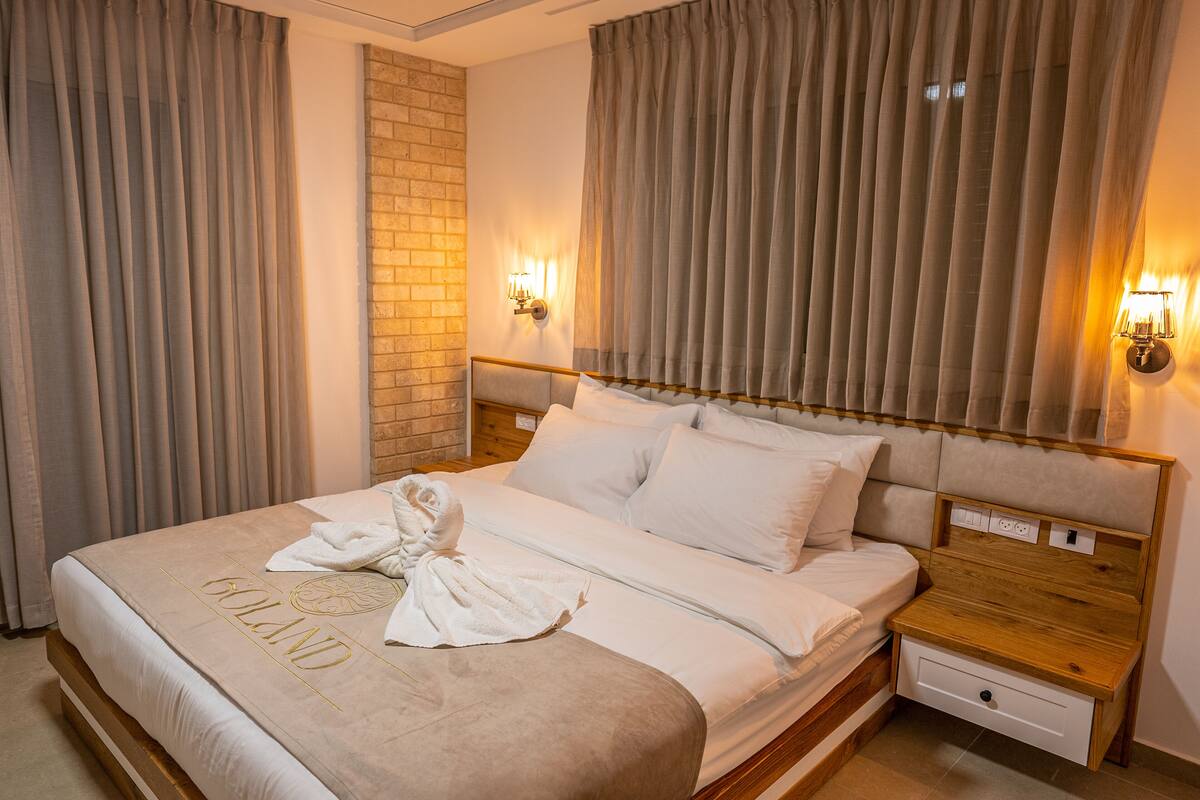 A hotel room with a bed, a wooden headboard, two bedside tables, and a brick accent wall.