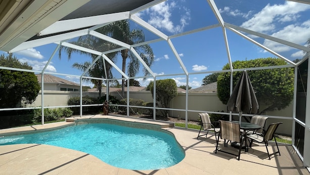 A covered outdoor area with a swimming pool, patio furniture, and a view of the surrounding neighborhood. - 441 Brentwood Ave (The Villages)