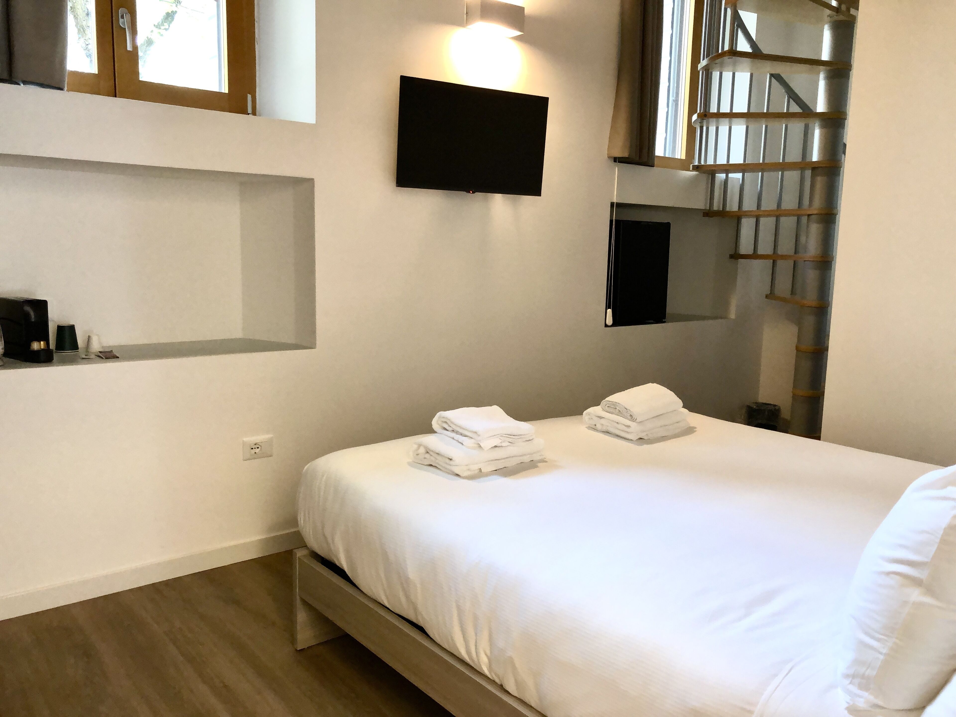 Une chambre à coucher avec un lit, un téléviseur à écran plat fixé au mur et une échelle en bois appuyée contre le mur.