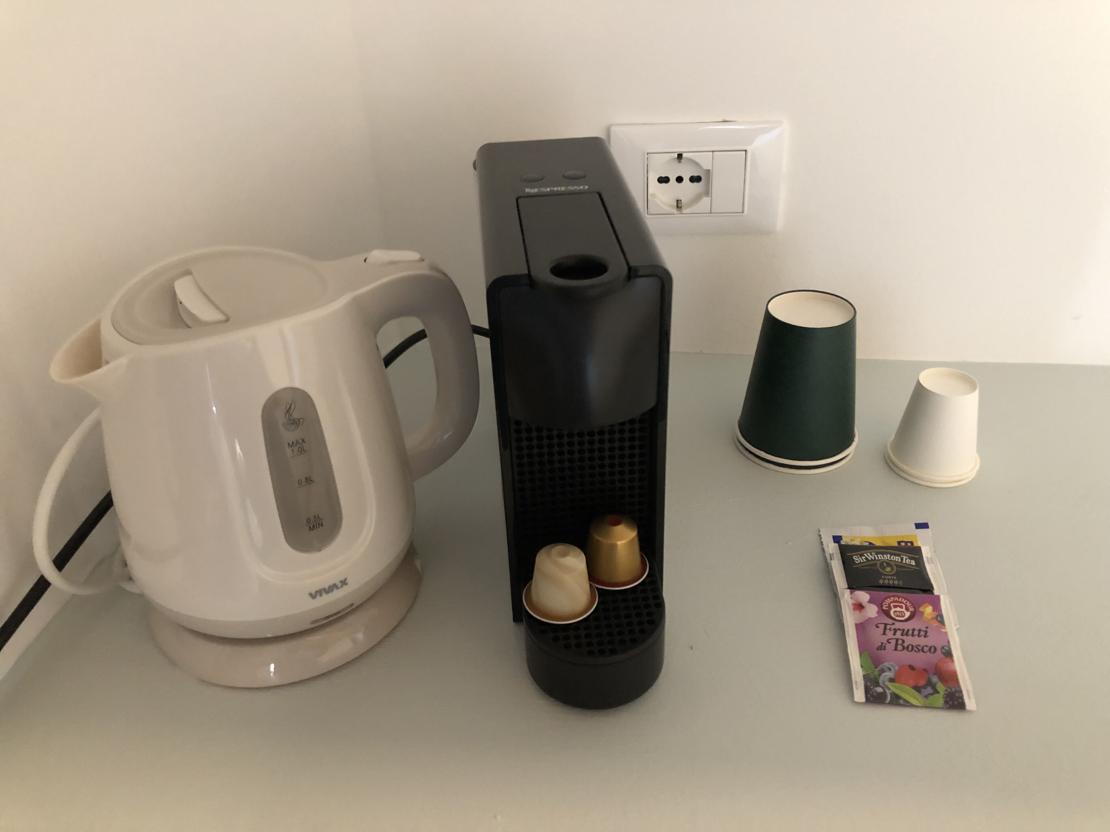 A coffee maker, a kettle, and a tea packet on a table.