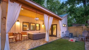 A cozy outdoor patio with a hot tub, seating area, and a well-maintained lawn. - Hot tub, Fireplace, Studio, Close to Main St. (Fredericksburg)
