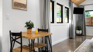 A dining area with a wooden table and chairs, a potted plant, and a glass of orange juice. - Hot tub, Fireplace, Studio, Close to Main St. (Fredericksburg)