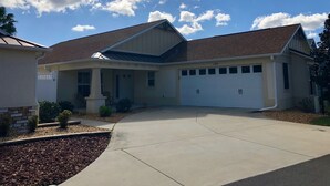 A two-story house with a garage, a covered porch, and a well-maintained driveway. - 1194 Flamingo Pl (The Villages)