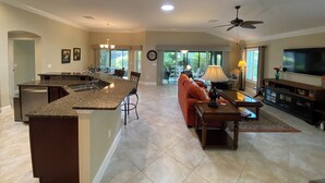 A spacious living area with a kitchen island, a sofa, a coffee table, and a television. - 1352 Kilgore Way (Wildwood)