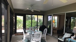 A sunlit patio area with a glass door leading to a garden, a table with chairs, and a ceiling fan. - 1352 Kilgore Way (Wildwood)