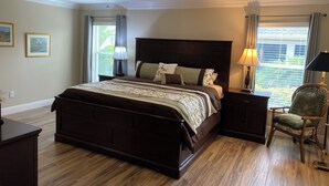 A bedroom with a large bed, a ceiling fan, a nightstand, a chair, and a window with curtains. - 1352 Kilgore Way (Wildwood)