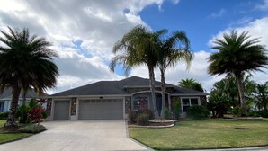 A single-story house with a garage, surrounded by palm trees and well-maintained lawns. - 1352 Kilgore Way (Wildwood)