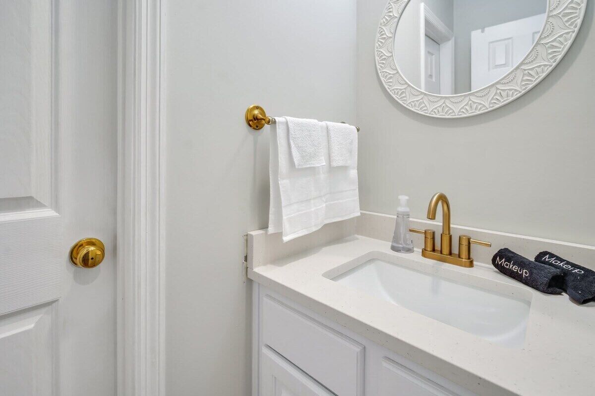 Une salle de bain avec un lavabo blanc, un robinet doré et un porte-serviettes sur lequel est posée une serviette blanche.