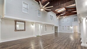 A spacious interior with high ceilings, wooden floors, and multiple windows. - Freedom's Flight - The Post Lofts (Statesboro)