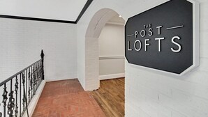 A staircase with a black sign reading "THE POST LOFTS" on a white brick wall. - Freedom's Flight - The Post Lofts (Statesboro)