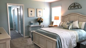 A bedroom with a bed, bedside tables, a nightstand, a lamp, and a wall-mounted decoration. - 5597 Sharpin St (Wildwood)