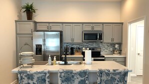 A modern kitchen with a central island, stainless steel appliances, and a backsplash. - 5597 Sharpin St (Wildwood)