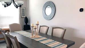 A dining room with a dark wooden table, striped placemats, and candle holders. - 5597 Sharpin St (Wildwood)