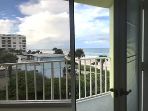 Un balcon avec vue sur l’océan et un bâtiment en arrière-plan.