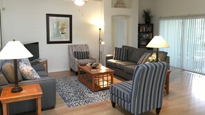 A living room with a sofa, armchairs, a coffee table, and a TV. - 1868 Poppy Cir (The Villages)