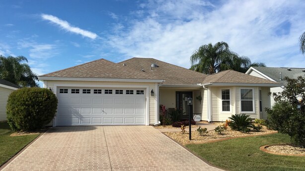 A single-story house with a garage, a front porch, and a well-maintained lawn. - 1868 Poppy Cir (The Villages)