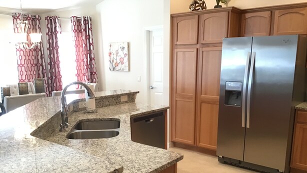 Una cocina con encimeras de granito, electrodomésticos de acero inoxidable, armarios de madera y lavavajillas integrado.